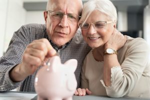 retired couple dropping coin in piggy bank Agile Wealth